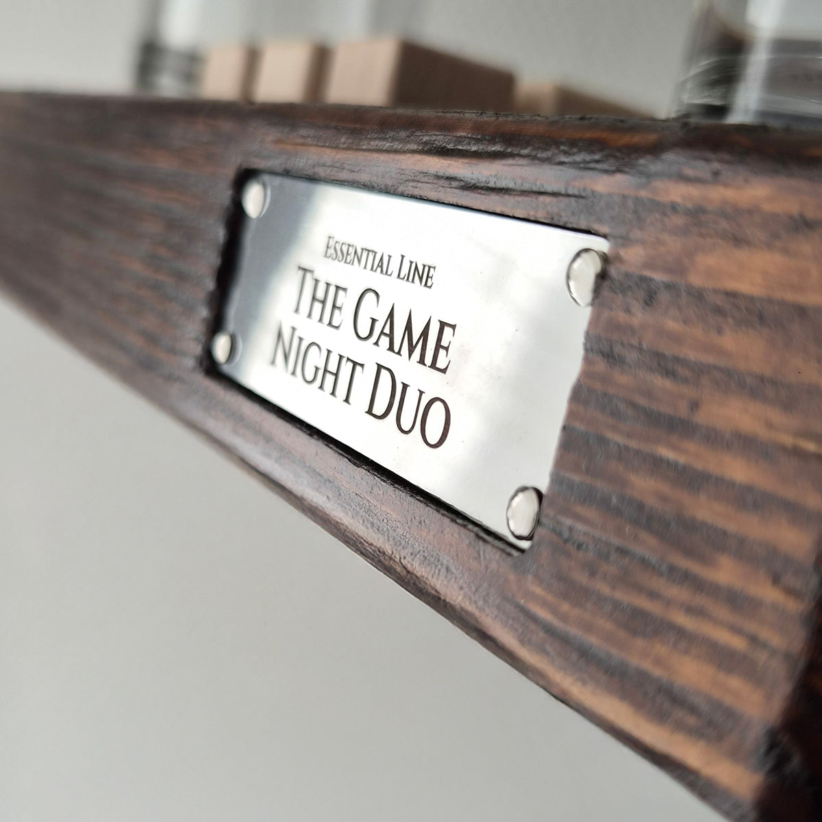Close-up van de metalen The Game Night Duo merkplaat op het massief houten drankspel voor twee.