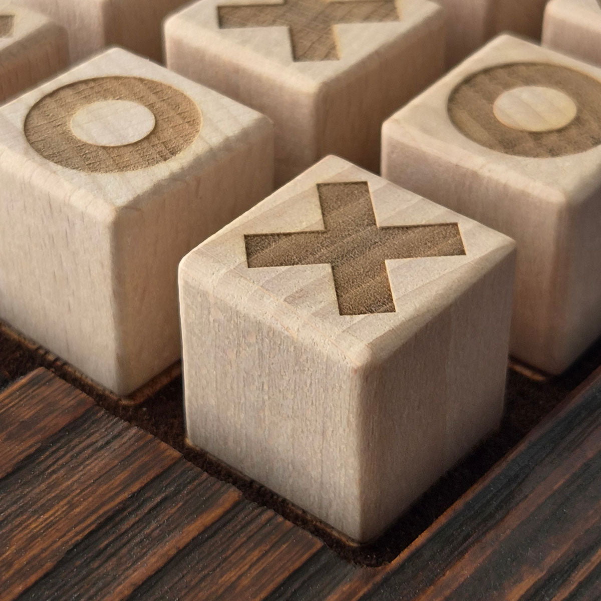 Close-up van houten speelblokjes met gegraveerde kruisen en cirkels in The Game Night Duo.