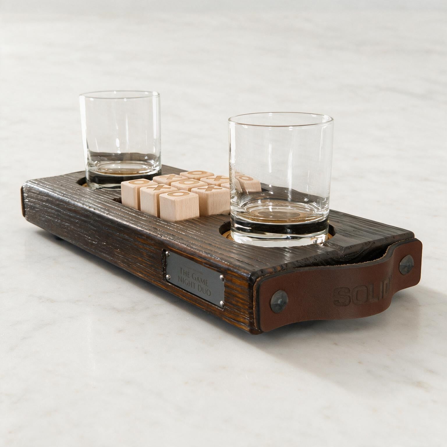 The Game Night Duo van donker massief hout met twee gegraveerde glazen en negen houten speelblokjes op wit steen